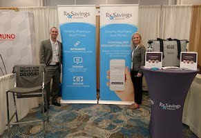 Two Rx Savings Solutions employees stand in front of our exhibition booth at the 27th Annual Health Benefits Conference & Expo