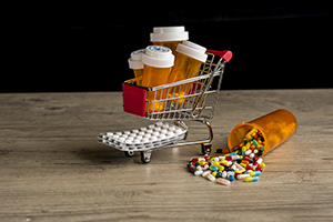 Prescription drug bottles sit in a miniature shopping cart